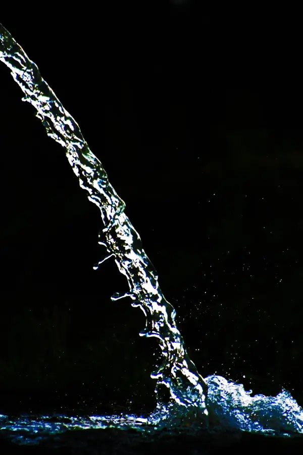 Un chorro de agua iluminado sobre un fondo oscuro